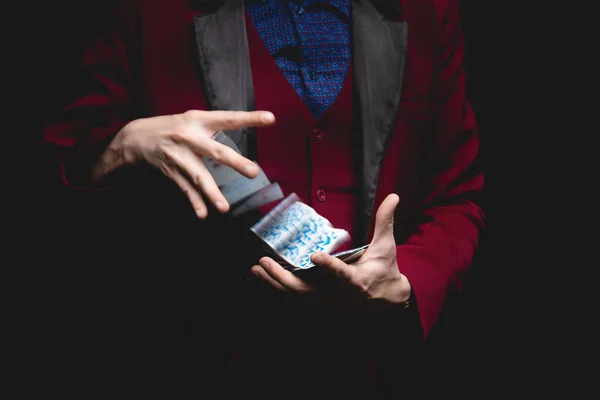 Чарівник показує трюк з граючими картками на темному тлі, пробіл для копіювання — стокове фото