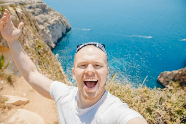 Glad turist man ler tar selfie foto på bakgrunden Blue Grotto i Malta. Begreppet Medelhavsresa — Stockfoto