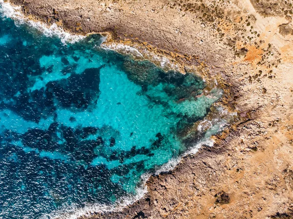 Vista superior Mar azul azulado con olas golpeando en la playa y rocas. Foto aérea . — Foto de Stock