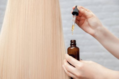 Yakından bir damla yağ alınır ve saç teli baş ampullerine uygulanır. Kuaför spa salonu kavramı