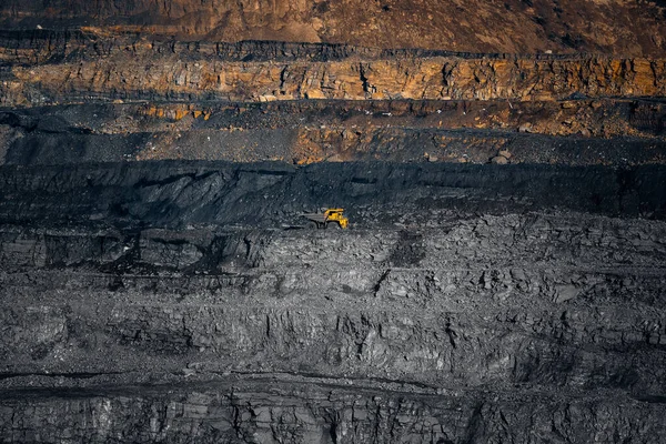Open mine minerals mining of coal, gold, diamonds, copper. Scale of quarry, large yellow dump truck for ore transportation on dark background — Stock Photo, Image