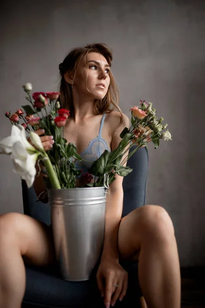 Bella giovane donna in biancheria intima blu pizzo tiene fiori di rosa, concetto di cura della pelle — Foto Stock