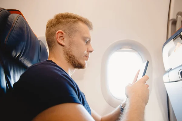 Człowiek używa inteligentnego telefonu komórkowego w samolocie kabinowym, koncepcja Internet w stratosferze powietrznej — Zdjęcie stockowe