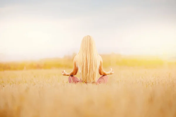 Chica rubia en el parque meditando lotos, pelo largo, su espalda se convierte en marco. Composición central, concepto de libertad — Foto de Stock