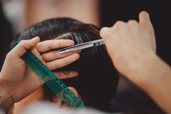 Barbershop concept. Man barber in men hairdresser does hair with scissors