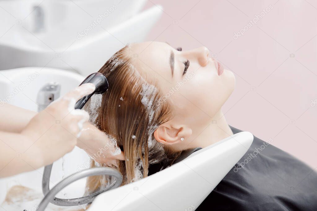 Beautiful blond woman getting hair wash in beauty salon