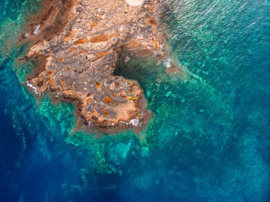 Azure temiz su mercan plajının kayalık sahilleri vurur. Havadan üst görünüm