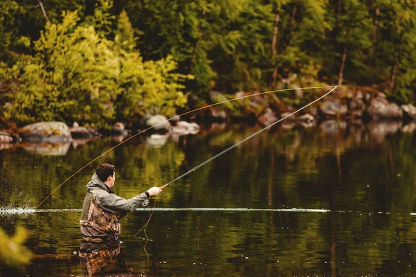 Pescador con varilla pesca con mosca en el río de montaña otoño salpicaduras de agua — Foto de Stock