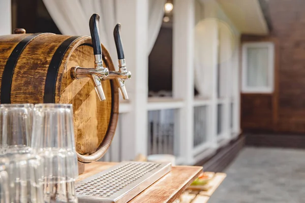 Wooden keg with taps for beer pouring drink into mugs bar, summer parties