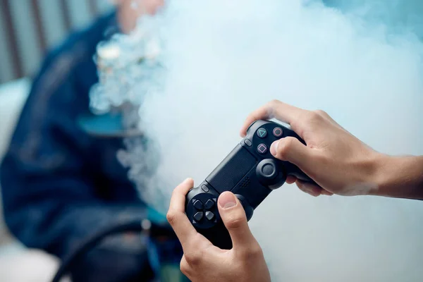 L'uomo tiene il gamepad in mano, in sottofondo il fumo del narghilè — Foto Stock