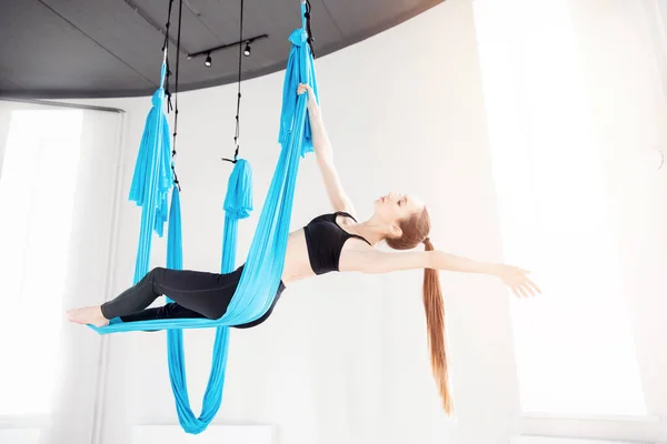 Wanita muda melakukan latihan yoga anti gravitasi udara di studio putih — Stok Foto