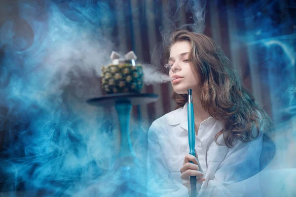 Młoda piękna kobieta w klubie nocnym dymu hookah lub shisha bar, niebieskie tło — Zdjęcie stockowe