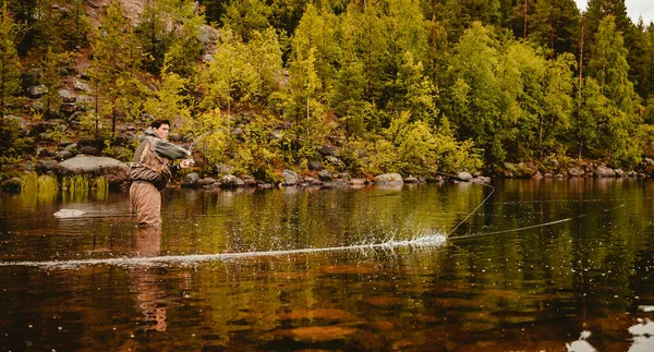 Rybář pomocí prutu muška rybaření v horské řece podzim stříkající vody — Stock fotografie