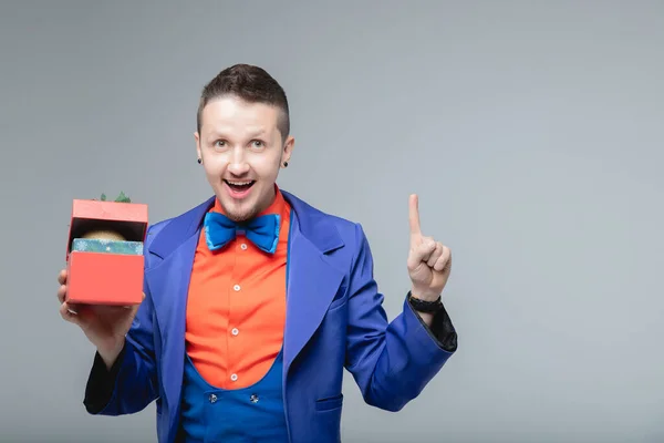 身穿蓝色西服的儿童魔术师拿着装有礼物的礼品盒，并指出他的手指复制空间作为文字。 圣诞佳节的概念 — 图库照片
