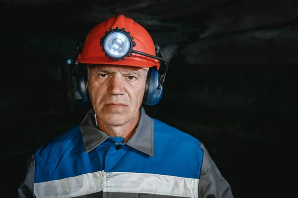 Portret górnika w hełmie z latarnią w podziemnej kopalni. Koncepcja inżyniera przemysłowego — Zdjęcie stockowe