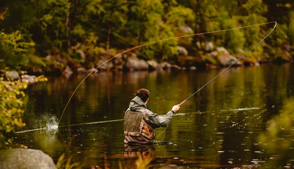 Pescador usando vara pesca com mosca no rio da montanha — Fotografia de Stock