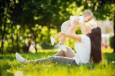 Anne bebeği kusar, doğada güneş altında oynar ve güler. Dışarıda mutlu bir aile
