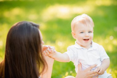 Mutlu bir aile, parkta çocuklu genç bir anne, öpücükler ve gülücükler oğlum. Güneşli yaz