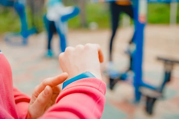 Menina esporte usa dedo toca pulseira fitness para medir a frequência cardíaca e número de passos, tecnologia útil — Fotografia de Stock
