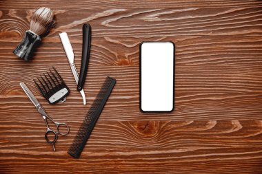 Eski ahşap arka planda cep telefonu ekranı olan kuaför berber araçları, üst görünümü kopyala