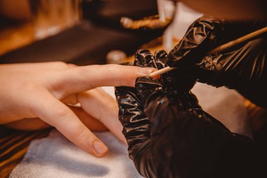 Adam kuaförde manikür yapıyor, usta tırnaklarını kesiyor.