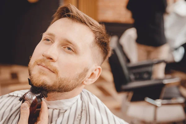 Крупный план парикмахерской, бреющей бороду мужчине в парикмахерской — стоковое фото