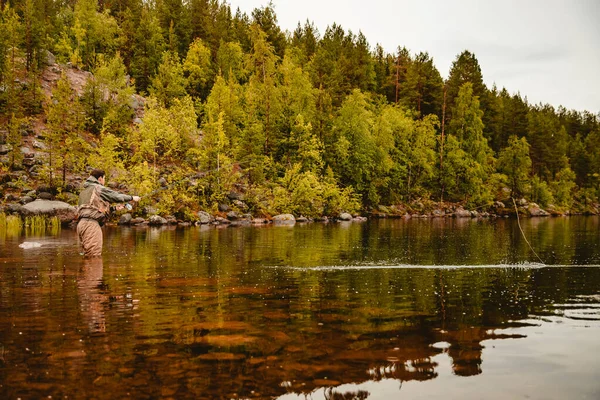 Pescatore con canna pesca a mosca in montagna fiume autunno spruzzi d'acqua — Foto Stock