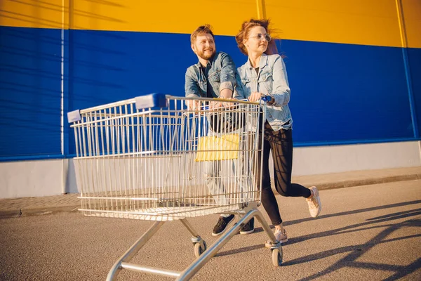Heureux jeune couple familial courir avec chariot pour stocker supermarché pour faire du shopping. Concept de style de vie — Photo