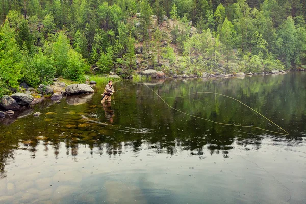 ブーツで山の川の漁師の男は、午前中に釣りサーモンフライ。空中展望 — ストック写真
