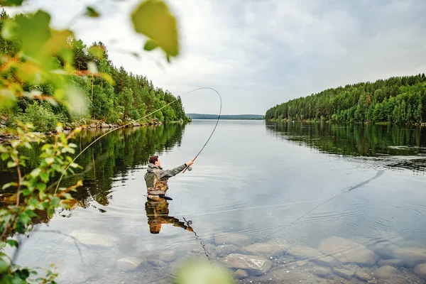 Pescador con caña pesca con mosca en río de montaña — Foto de Stock