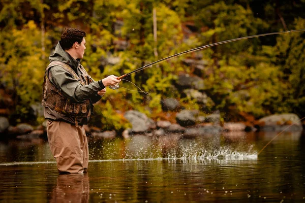 Pescatore con canna pesca a mosca nel fiume di montagna — Foto Stock