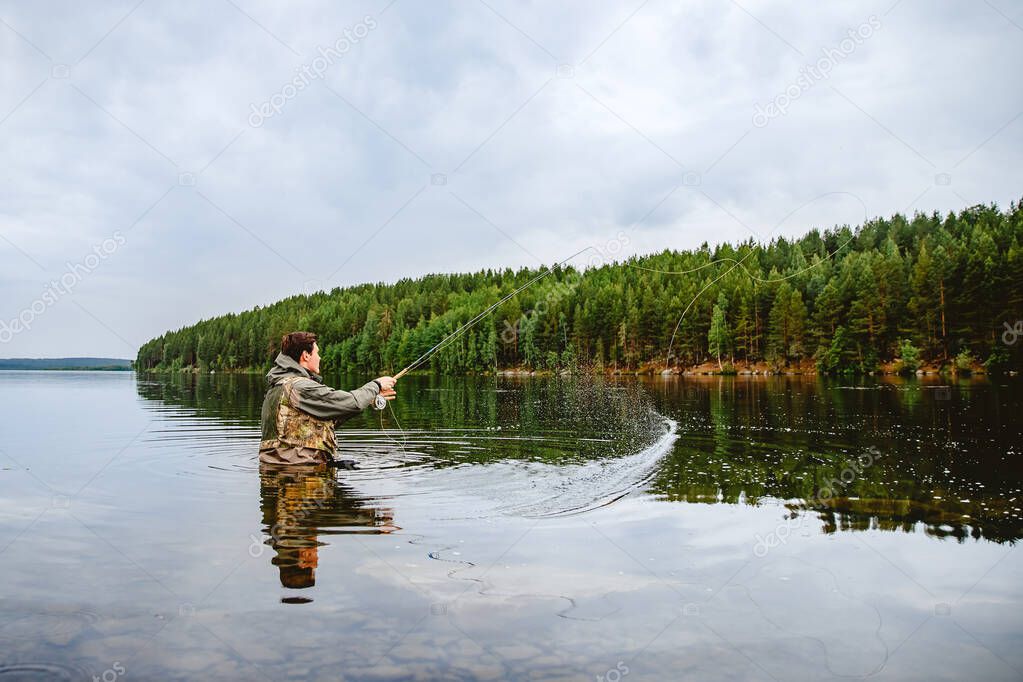 Fisherman using rod fly fishing in mountain river summer splashing water