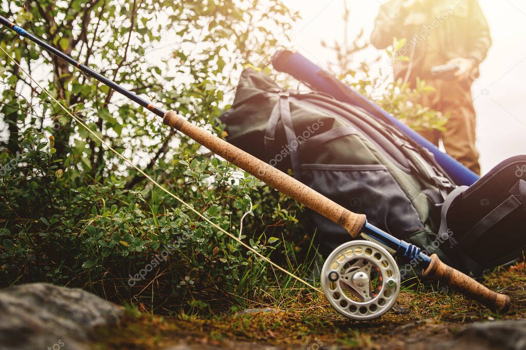 Fly fishing rod, hiking backpack, in background man dresses fisherman