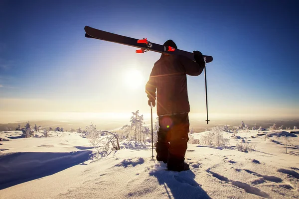 Homem esquiador fica com esqui no topo da montanha no fundo do nascer do sol. Freerida fresca da neve — Fotografia de Stock