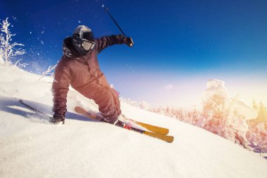 Dağlarda ve ormanda güneşli bir günde kayakçı yokuş aşağı kayıyor. Olağanüstü kış sporları