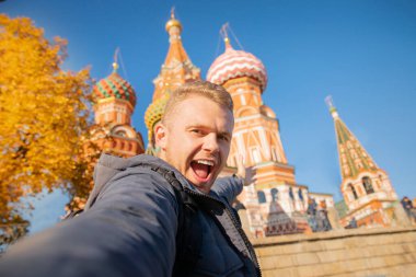 Male tourist makes selfie photo on background Saint Basil Cathedral Red Square in Moscow, Russia autumn. Travel concept clipart