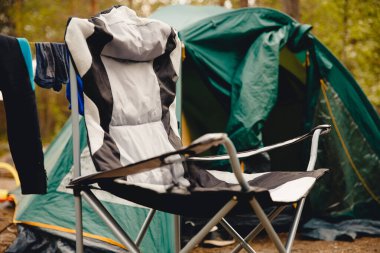 Kamp için katlanır sandalye, arka planda çadır var.
