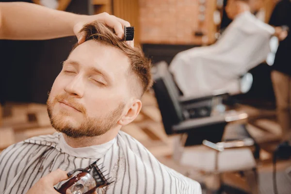 Крупный план парикмахерской, бреющей бороду мужчине в парикмахерской — стоковое фото