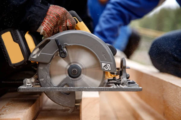 Bouwer gebruikt draagbaar cirkelzaaggereedschap om hout te zagen — Stockfoto