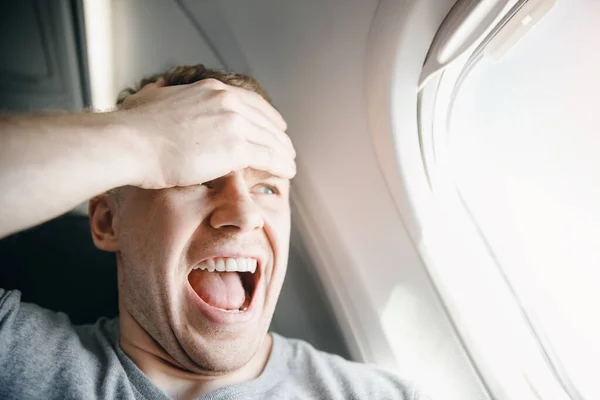 Passagier im Flugzeug klammert sich an den Kopf, hat Angst vor Höhe und Flug. schreien und weinen Ausdruck — Stockfoto