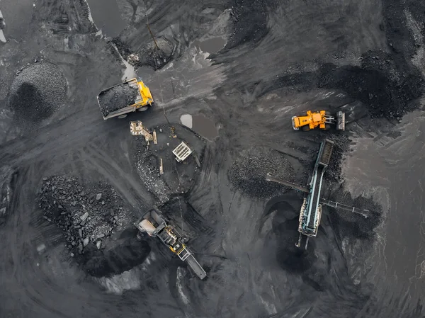 Open pit mine industry, excavator loads coal into an industrial crusher. Top view aerial