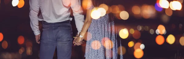 Romantisch paar in de liefde houdt handen tegen de achtergrond van de nacht stad lichten — Stockfoto