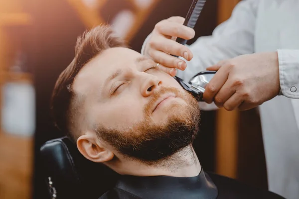 Close-up van kapper scheren baard tot man in kapperszaak elektrisch scheermes — Stockfoto