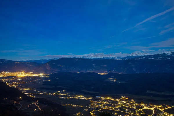 Vista noturna Bolzano cidade Itália contra pano de fundo de montanhas, luz de lanternas e estrelas — Fotografia de Stock