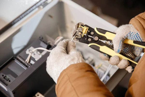 Master electrician with professional tool for removing insulation from power cable, installing networks — Stock Photo, Image