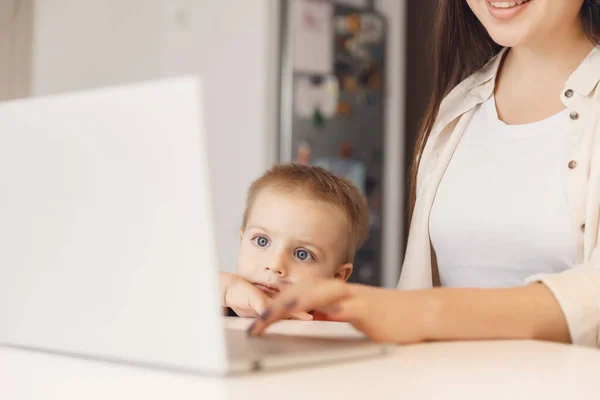 Biznes mama jest za pomocą laptopa pracy online, kobieta spędza czas ze swoim chłopcem baby home — Zdjęcie stockowe