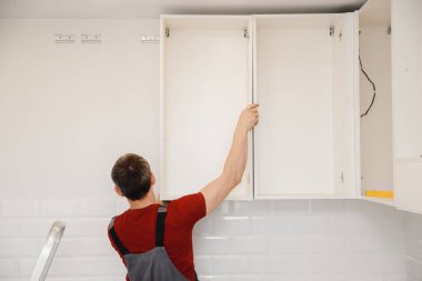 Mobilya dolabı menteşesi monte eden bir işçi. Mutfak tamircisi.