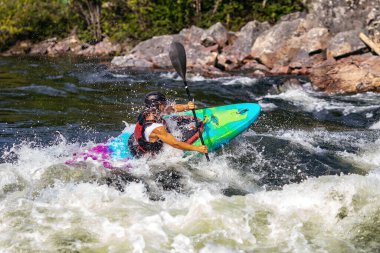 Ekstrem spor rafting beyaz su kayağı. Kanodaki adam dağ nehrine yelken açıyor.