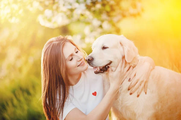 Genç bayan köpek Labrador Retriever 'a sarılıyor. Yeşil çimen parkında, yaz günü.