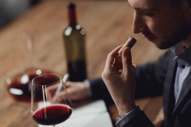 Şarap mantarı kokusunu inceleyen ve aroma degustasyonu kartı yazan profesyonel bir şarap garsonu.